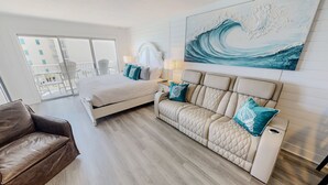 A hotel room with a bed, a sofa, a chair, a painting, and a balcony with a view. - Islander Beach Resort 407 1 Bedroom Condo (Fort Walton Beach)