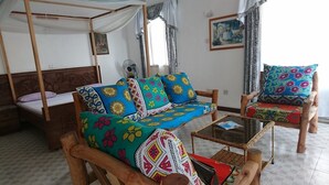 A room with a bed, a sofa, a chair, and a small table. - Punda Milia Paradise Hotel Shanzu (Mombasa)