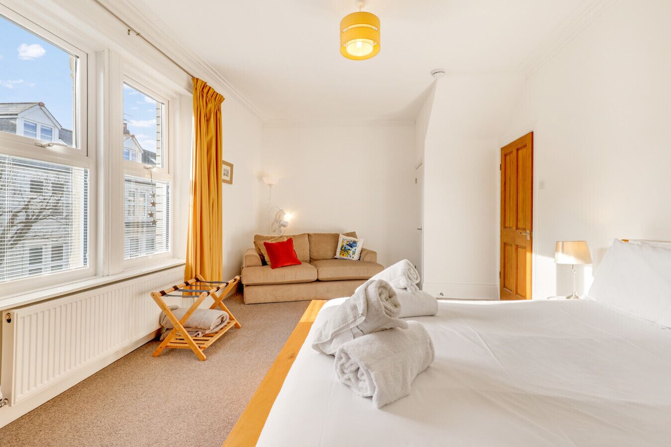 Ett hotellrum med en säng, en soffa, en trästol och ett fönster med gardiner.