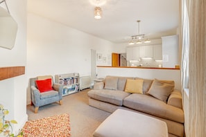 A living room with a sofa, armchair, and a bookshelf.