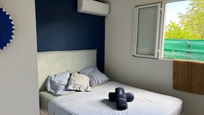 A bedroom with a bed, pillows, a window, and an air conditioning unit. - Villa Ti Kaz a Mymy - Pool villa St-François (Saint-François)