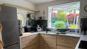 A modern kitchen with a corner island, stainless steel appliances, and a view of a garden. - Villa Ti Kaz a Mymy - Pool villa St-François (Saint-François)