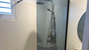 A glass-enclosed shower with a handheld showerhead, a white sink with a round mirror, and a woven basket on the floor. - Villa Ti Kaz a Mymy - Pool villa St-François (Saint-François)