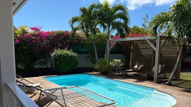 A swimming pool with a wooden deck, lounge chairs, and a pergola. - Villa Ti Kaz a Mymy - Pool villa St-François (Saint-François)