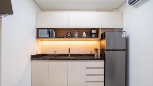 A compact kitchen with a microwave, coffee maker, and refrigerator. - Full Studios in Rio Tavares - ALA (Florianópolis)