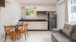 A compact kitchen with a dining area, a sofa, and a TV. - Full Studios in Rio Tavares - ALA (Florianópolis)