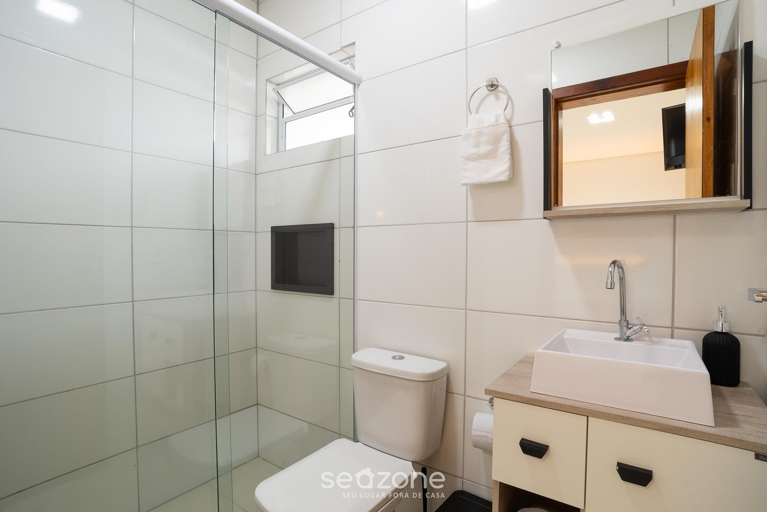 A bathroom with a glass shower enclosure, a white sink, and a mirror above the sink.