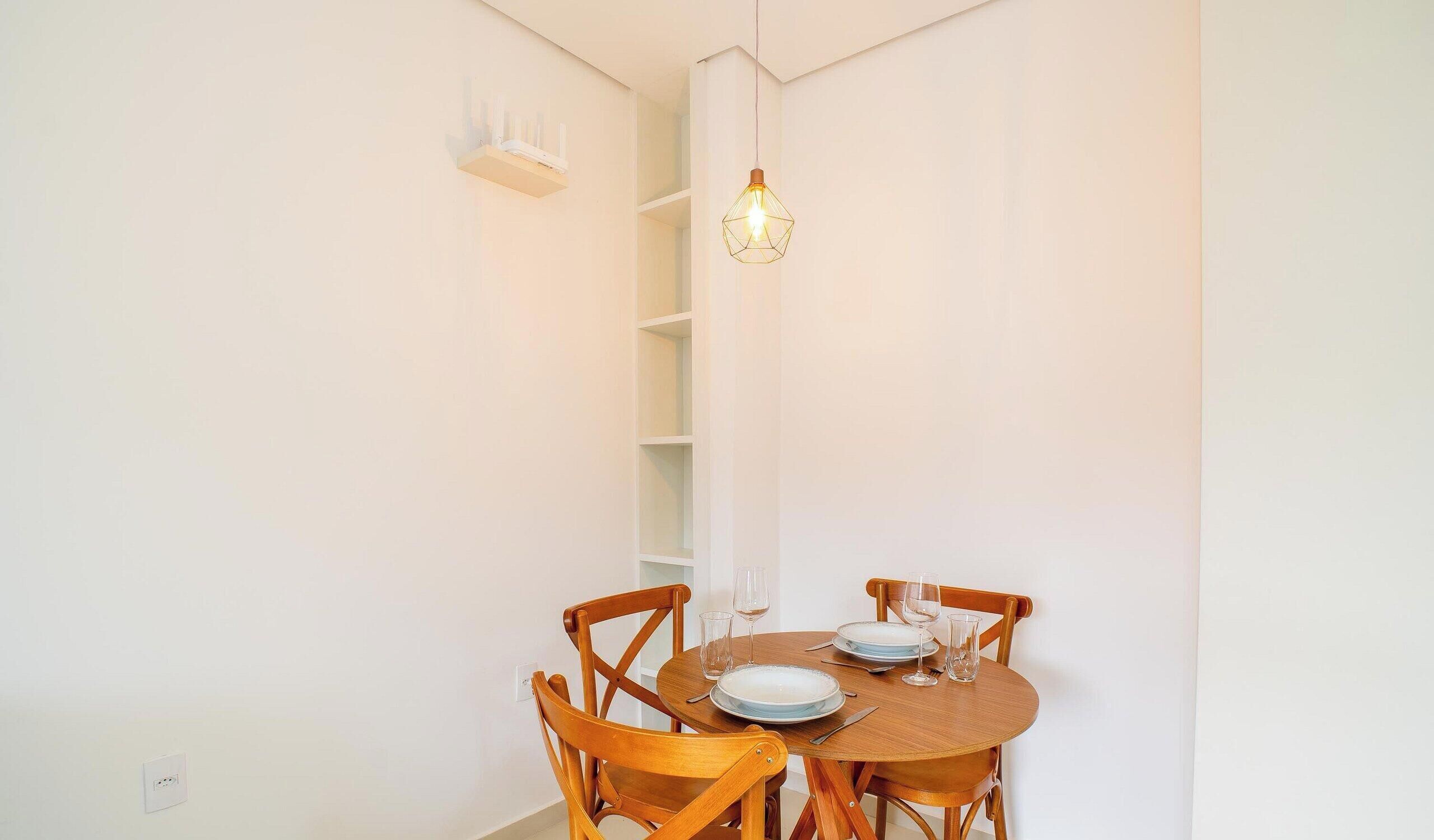 A dining area with a round table, wooden chairs, and a hanging light fixture.