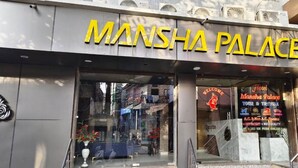 Entrada de un hotel con un cartel que dice 'Mansha Palace'.