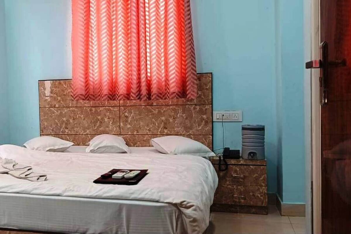 A hotel room with a bed, a nightstand, a water dispenser, and a door.