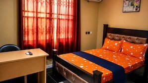 A hotel room with a bed, a desk, and a window with curtains. - Kwae Delux Hotel (Mile 11)