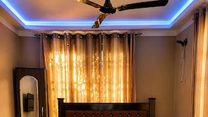 A bedroom with a bed, a ceiling fan, and curtains. - Kwae Delux Hotel (Mile 11)