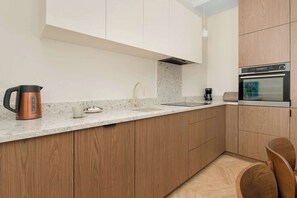 Une cuisine moderne avec des meubles en bois, un four en acier inoxydable, une machine à café et une bouilloire.