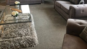 Una sala de estar con dos sofás, una mesa de centro de vidrio y una alfombra mullida.