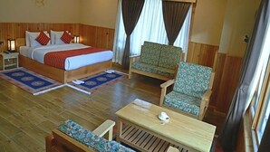 A hotel room with a bed, two chairs, a table, and a window with curtains. - River Front Resort (Paro)