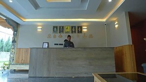 A reception desk with a person behind it, a wall with framed pictures, and a ceiling with recessed lighting. - River Front Resort (Paro)