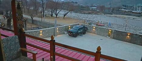 Un balcone con vista su un fiume, un veicolo parcheggiato e un edificio sullo sfondo.