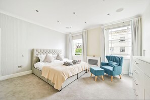 Ein Schlafzimmer mit einem Bett, einem Sessel, einem Fenster und einer Heizung.