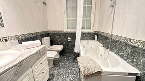 Un baño con lavamanos, inodoro, bañera y cortina de ducha de mármol.