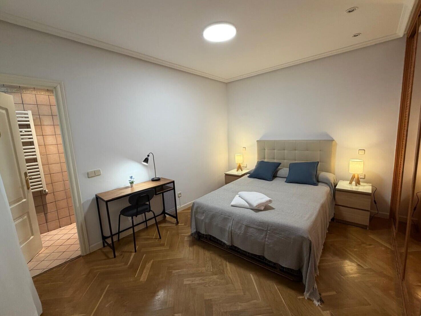 Ein Schlafzimmer mit Bett, Nachttischen, Schreibtisch und Stuhl.