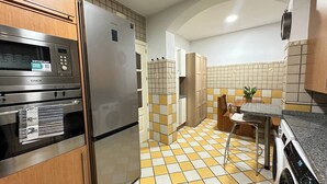 Una cocina con microondas, horno, refrigerador, salpicadero de azulejos y zona de lavamanos.