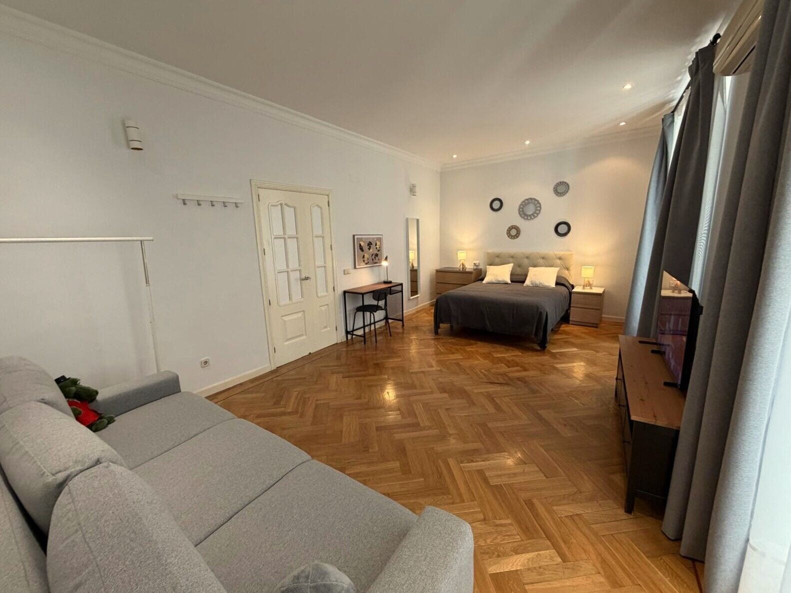 Ein modernes Wohnzimmer mit einer Couch, einem Bett, einem Schreibtisch und einem Sessel.