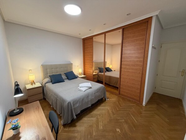 Camera d'albergo con un letto, comodini, una scrivania, una sedia, una pianta in vaso e un armadio con specchio.