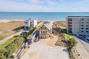 Een hotel aan de kust met uitzicht op het strand, meerdere verdiepingen en een parkeerplaats.