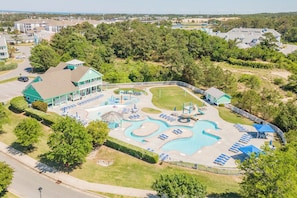An aerial view of a resort with a swimming pool, sun loungers, and a small building.