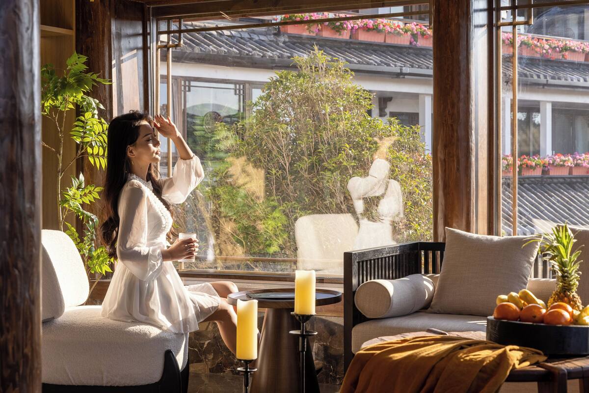 A room with a view of a traditional building, a table with candles, and a bowl of fruit.