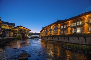 A traditional building with a stone wall and a bridge over a calm river. - Lijiang Fog Gallery Hotel (Lijiang)