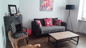 Een woonkamer met een bank, een houten salontafel, een fauteuil met een patroon, een rode fitnessbal en een vloerlamp.