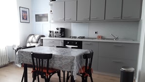Een kleine keuken met een eettafel, stoelen en een afvalbak.