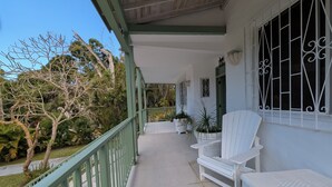 A covered porch with white wicker furniture, a green railing, and potted plants. - Close to shops and Restaurants, Family friendly, 5 minutes to beach (Holetown)