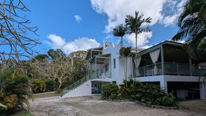 A two-story building with a covered outdoor area, a staircase, and surrounding greenery. - Close to shops and Restaurants, Family friendly, 5 minutes to beach (Holetown)