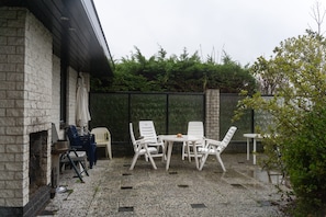 A patio with outdoor seating, a brick wall, and a green fence. - Villa KAREKIET in a prime location in Sint Maartenszee, accommodating 8 people (Sint Maartensvlotbrug)