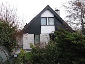 A two-story house with a gabled roof, a visible chimney, and a small garden area in front. - Villa KAREKIET in a prime location in Sint Maartenszee for 8 people (Sint Maartensvlotbrug)