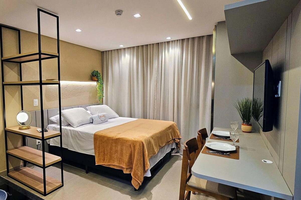 Ein Hotelzimmer mit einem Bett, einem Schreibtisch mit Stuhl, einem Fernseher und einem Fenster mit Vorhängen.