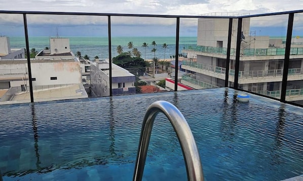 Une piscine à débordement offrant une vue sur l’océan et les bâtiments.
