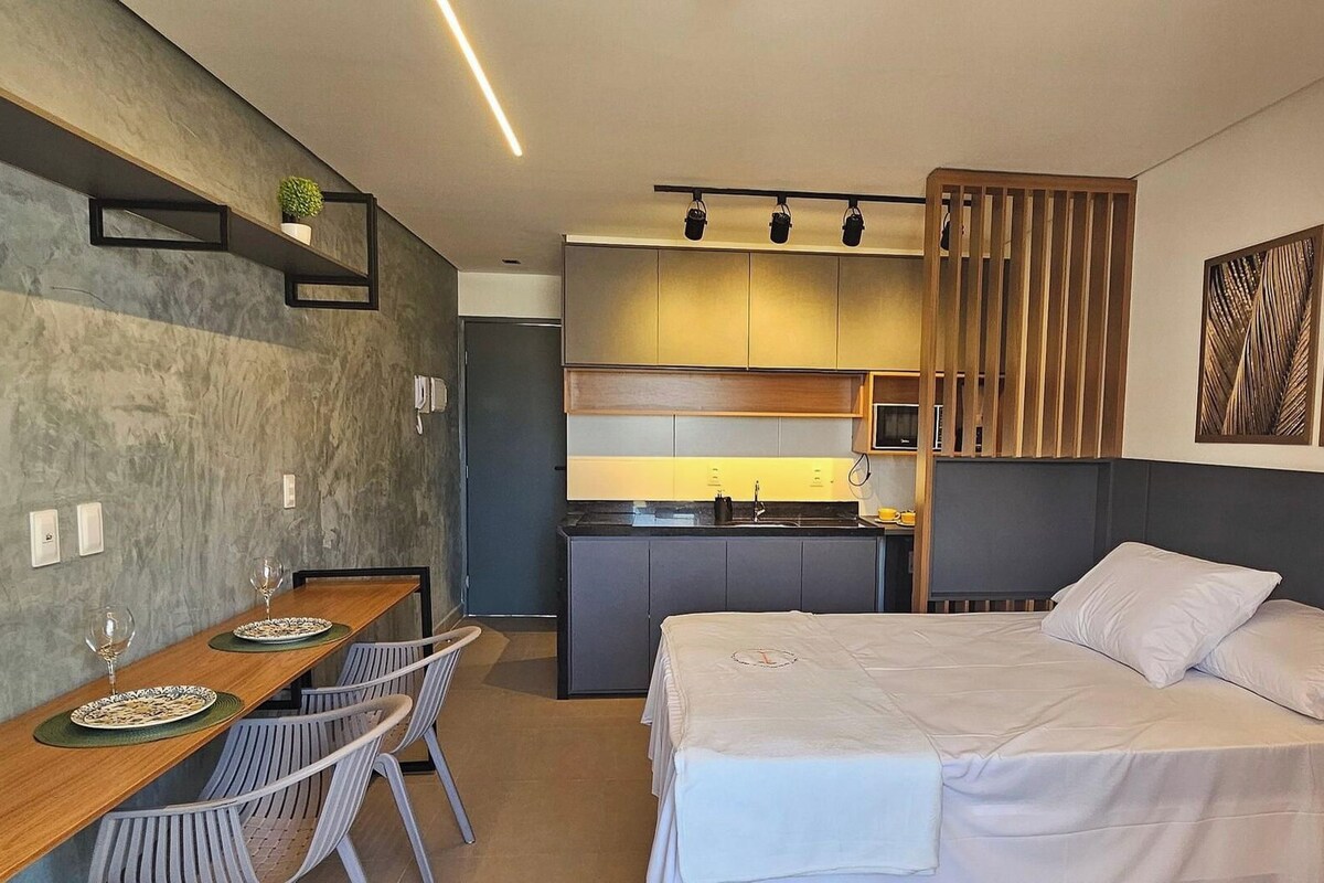 Une chambre d’hôtel de taille réduite comprenant un lit, une petite kitchenette, un coin repas et une salle de bain.