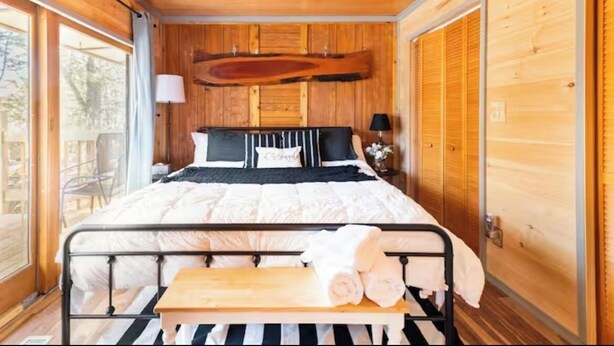 Ein Zimmer in einer Holzhütte mit Bett, Deckenventilator und einer Bank.