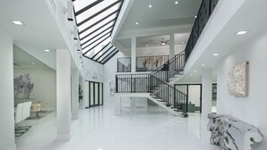 Een ruim, modern interieur met een centrale trap, hoge plafonds en een gepolijste vloer.