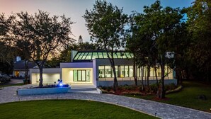 Een modern huis met een verzorgd gazon, een oprit en een klein waterpartij.