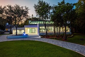 A modern house with a well-maintained lawn, a driveway, and a small water feature. - 8,000 sq ft Estate with Heated Pool & Game Room (Plantation)