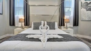 Hotellihuone, jossa on suuri sänky, kaksi yöpöytää valaisimineen, sängynpääty ja taulu seinällä.