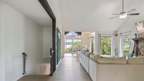 Un long couloir étroit, avec un plancher en bois, un canapé et un ventilateur de plafond.