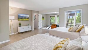 Une chambre spacieuse avec deux lits, une grande fenêtre, un balcon et une vue sur la verdure.
