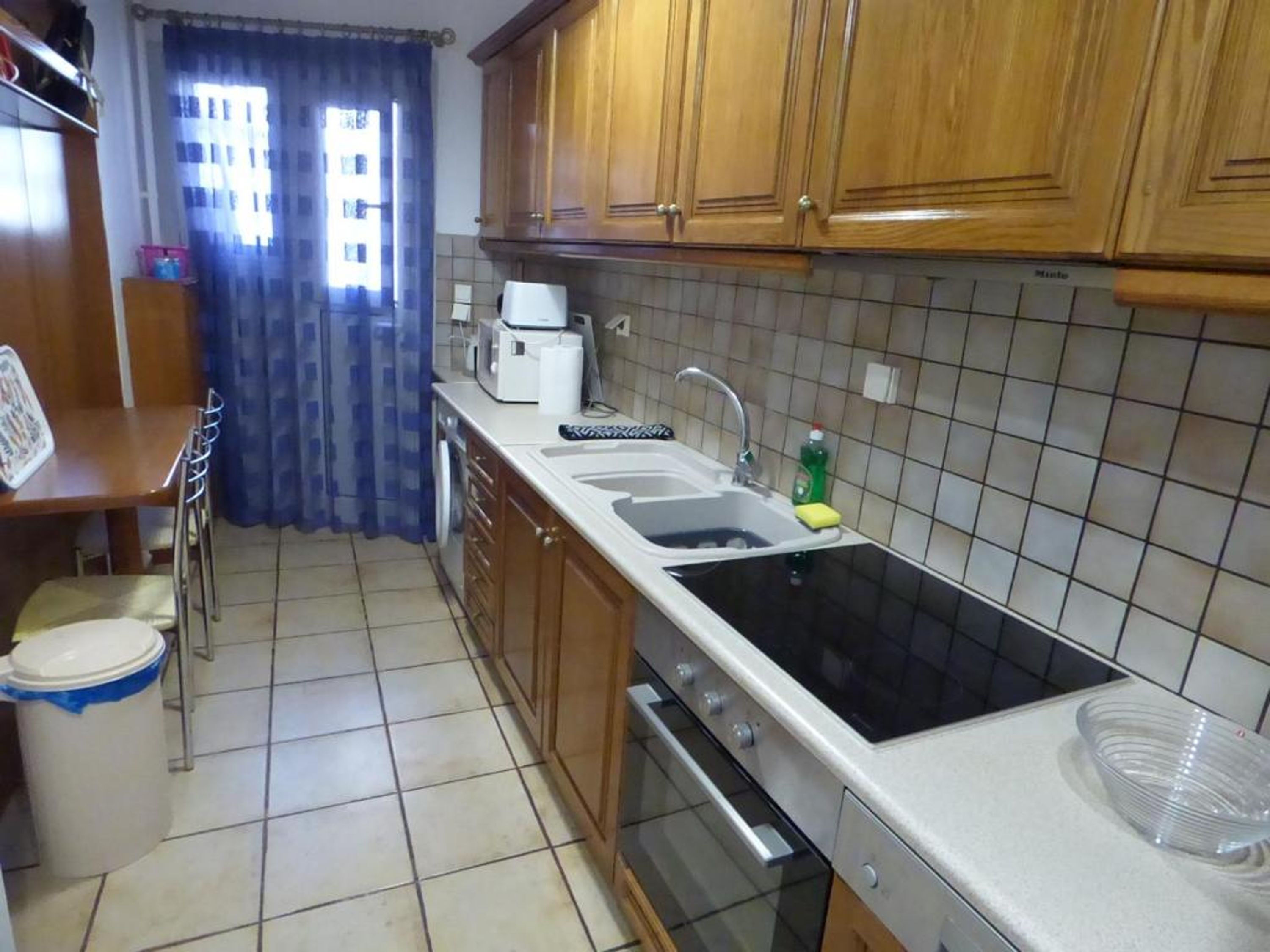 Une cuisine avec des meubles de rangement en bois, un évier à deux bacs, un four à micro-ondes et une cuisinière.
