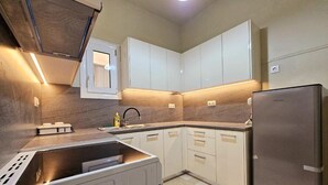 A modern kitchen with white cabinets, a stainless steel refrigerator, and a built-in oven. - El Prestige Apartment - Athens Town (Athens)
