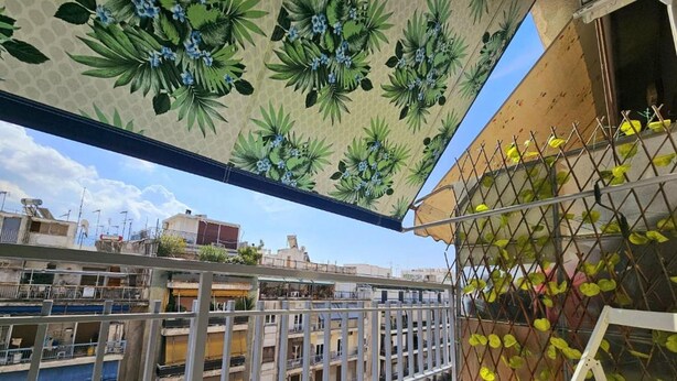A balcony with a view of buildings, a metal fence, and a plant-covered wall. - El Prestige Apartment - Athens Town (Athens)